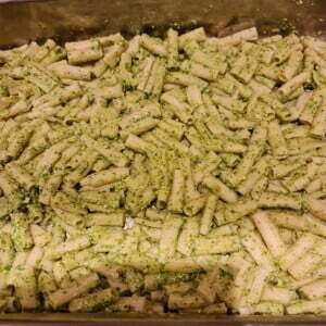 Green pesto covered pasta spread evenly