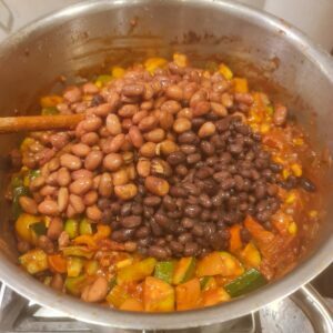 Adding the veggies and beans to the chilli
